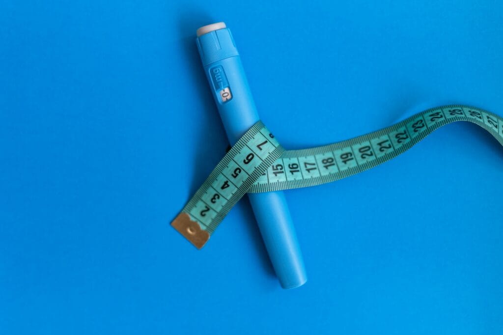 Navigating the Changing Landscape of Tirzepatide Availability: How the FDA’s Announcement Affects Generic Alternatives and Patient Care 3 Ozempic injector drug with a measuring tape on a blue background.